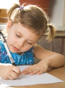 small girl learns to write, sits at a table