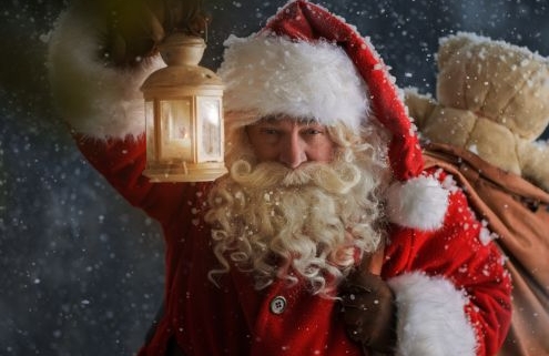 A képen a Mikulás egy lámpást tart a kezében, a zsákja a hátán. Kint áll a hóesésben, csak az arcát látjuk.