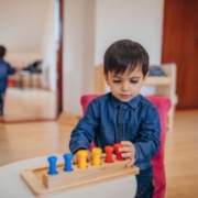 Felkészülés az iskolára - figyelem. A képen egy kisfiú elmélyülten játszik fa játékokkal