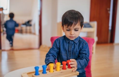 Felkészülés az iskolára - figyelem. A képen egy kisfiú elmélyülten játszik fa játékokkal