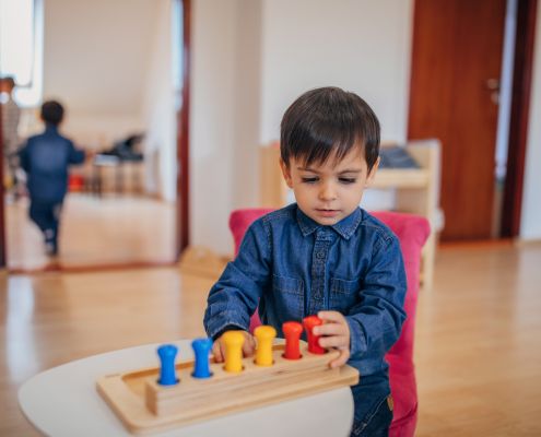 Felkészülés az iskolára - figyelem. A képen egy kisfiú elmélyülten játszik fa játékokkal