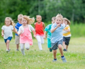 A képen óvodás korú gyermekek futnak kint a szabadban