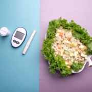 A kép baloldalán a vércukorméréshez használt eszközök, egy doboz gyógyszer látható, jobb oldalon pedig saláta egy tányéron.