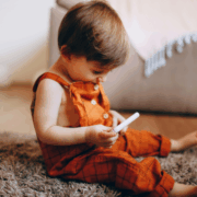Diabéteszpótlék a bölcsődében - egy kisgyermek a földön ülve a vércukormérőt nézegeti