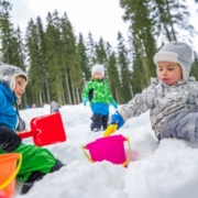 Téli játékok a természetben - kisgyermekek játszanak kint a hóban hólapáttal