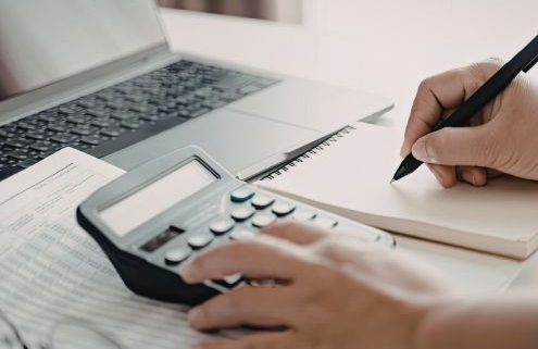 A szolgáltatási önköltség megállapítása április 1-jéig - a kiemelt képen egy női kéz számológéppel kalkulál, a hölgy jobb kezében van egy toll és jegyzetel