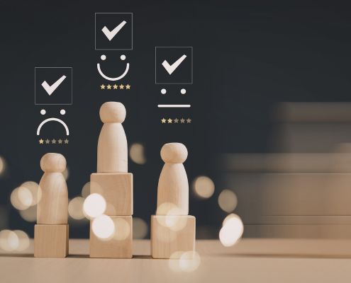 Részmunkaidős munkavállaló teljesítményértékelése - a képen fabábukat láthatunk fakockákon, a "fejük" felett az értékelést jelző csillagok, és az értékelésnek megfelelő smiley