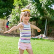 Egy kislány a szabadban babzsákot egyensúlyoz a fején