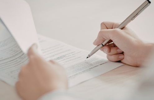 A kiemelt képen valaki aláír egy hivatalos iratot tollal a kezében