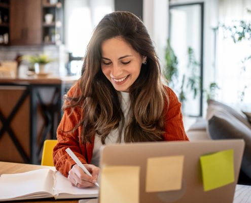 Hogyan készüljünk a minősítési eljárásra - mosolygós nő dolgozik egy laptop mögött