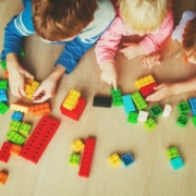 A képen három kisgyermek legózik hason fekve