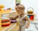 A képen egy fejpántos kislány játszik szövött kosarakban lévő játékokkal